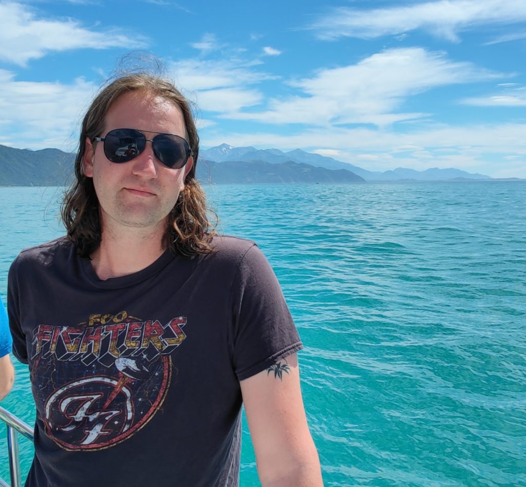 A photo of me with the turquoise blue water of the ocean behind me.